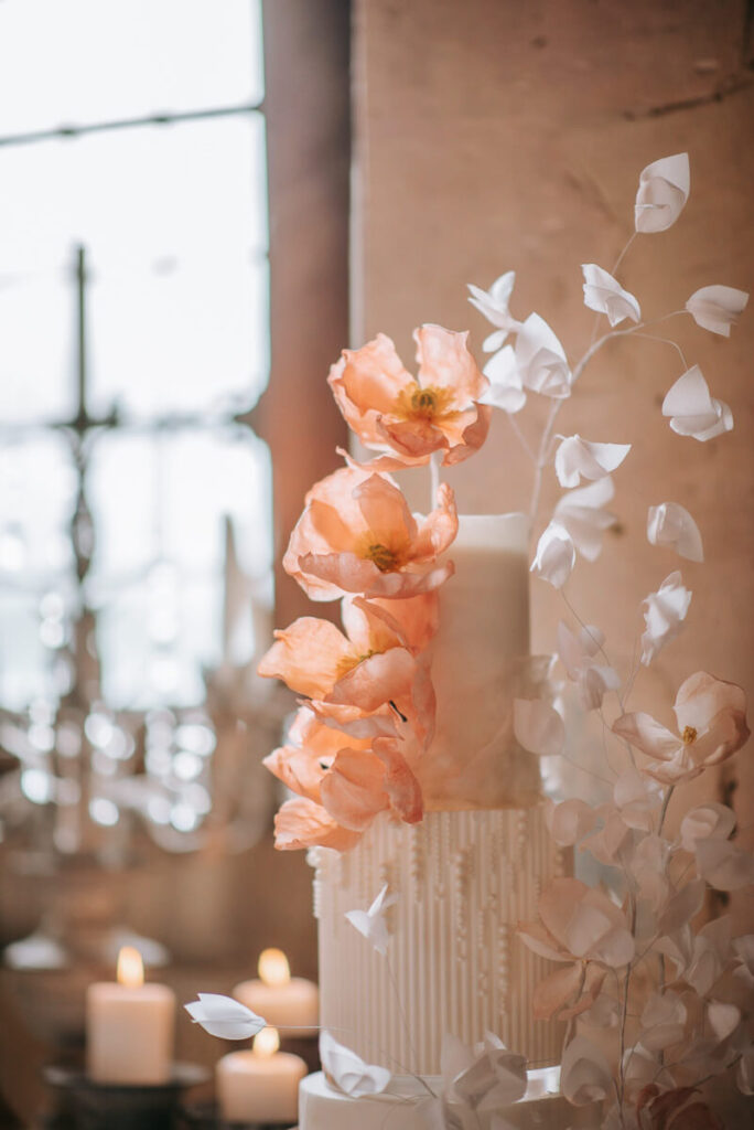 A glorious wedding cake with pretty pink flowers on display in the Priory near Ashford near Kent